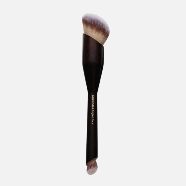 A dual-ended makeup brush with angled bristles on one side and a smaller rounded brush on the other, featuring a black handle with gold text—perfect for flawless application and ideal for your summer makeup tips routine.