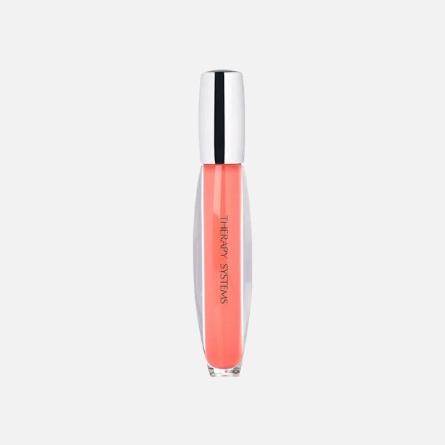 A clear tube of coral-colored lip gloss with a silver cap labeled "Therapy Systems," perfect for summer makeup tips, stands upright on a white background.