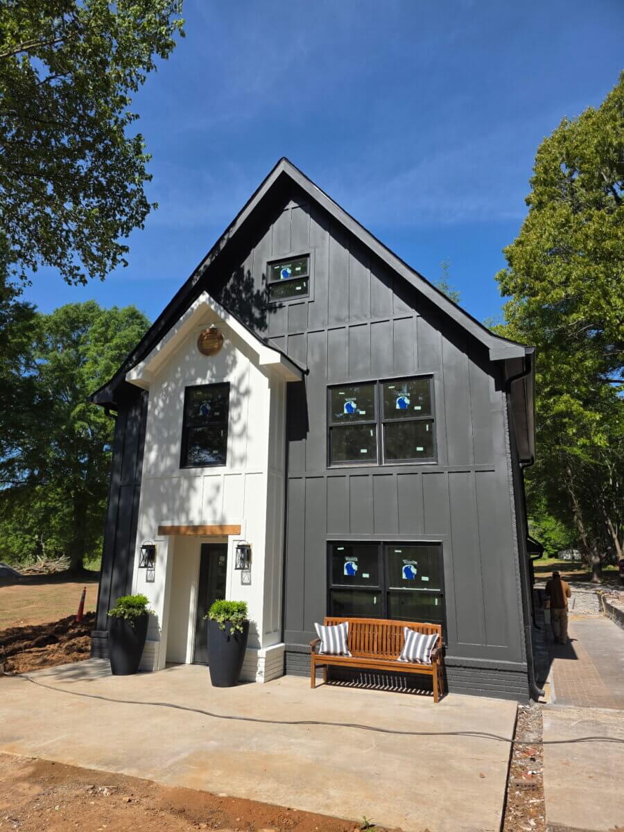 Need a Change of Scenery? Try These Summer Weekend Trips From Nashville - 12 Modern two-story house with black and white exterior, tall front entrance, large potted plants, a wooden bench, and multiple windows—a serene retreat perfect for relaxing after day trips from Nashville, surrounded by trees under a blue sky.