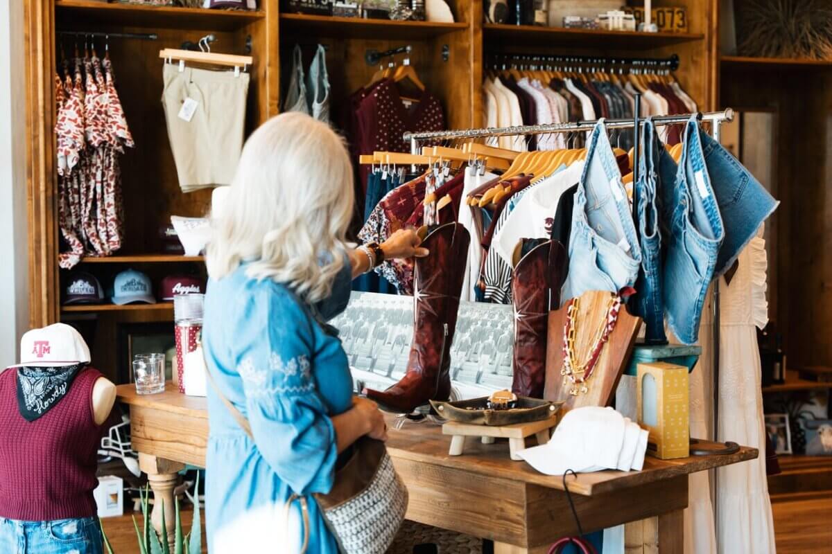 How to Eat, Shop & Play Your Way Through Texas - 3 A woman with white hair examines a pair of tall brown cowboy boots in a boutique filled with clothing and accessories—a classic stop on any list of things to do in Texas.