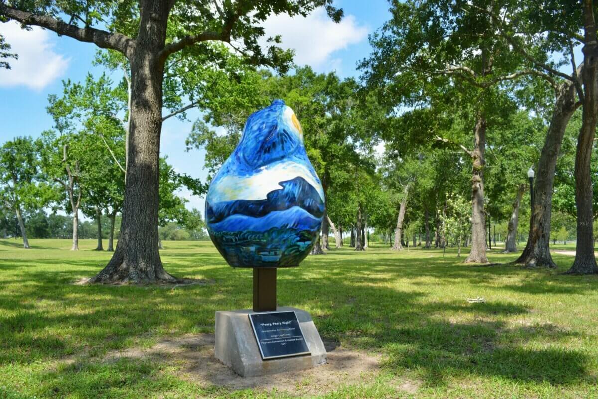 How to Eat, Shop & Play Your Way Through Texas - 13 A large pear-shaped sculpture painted with a mountain landscape stands on a pedestal in a grassy park surrounded by trees, making it one of the unique things to do in Texas for art lovers and outdoor enthusiasts alike.