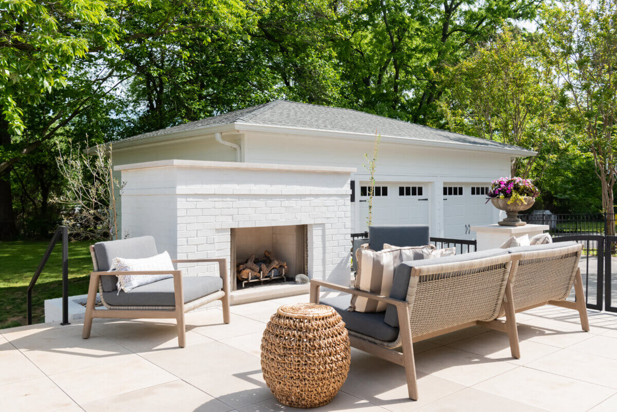 10 Designer Tips for Upgrading Your Outdoor Spaces - 8 An outdoor sofa faces a white custom fireplace with a chair next to it