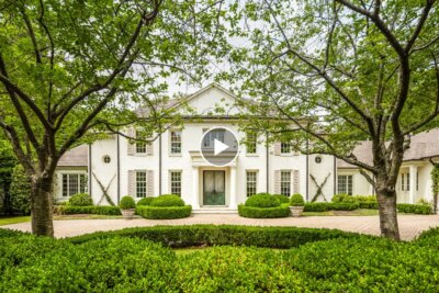 Elegant large white two-story house with columns in Memphis, surrounded by manicured bushes and trees, featuring a circular driveway in front. Located at 4068 Robinwood Cv.