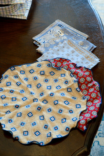 The Event-Season Trends Nashville Boutiques Are Loving Right Now - 12 Several patterned pocket squares and rounds, including beige, blue, and red designs, are arranged on a dark wooden table, adding a touch of formal fashion to the setting.