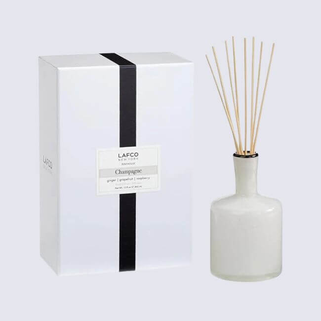 17 Luxurious Birmingham FINDS: Polished Summer Style, Artful Decor & Everyday Luxuries - 14 A luxurious white box labeled "Lafco Champagne" stands next to a white diffuser bottle with reed sticks inserted, bringing a touch of Birmingham elegance and summer freshness to any space.