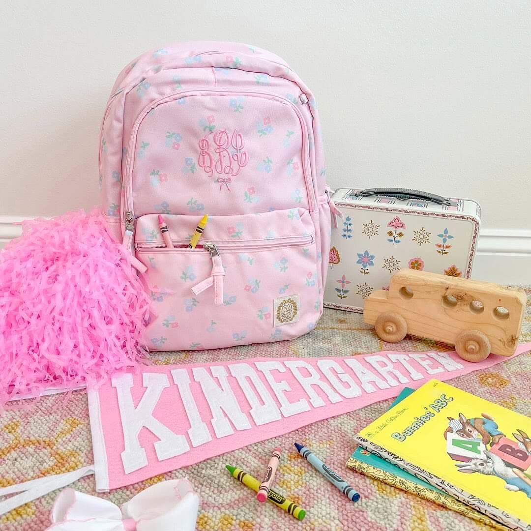 8 Birmingham Children's Boutiques for Every Age - 6 A pink backpack, lunchbox, wooden toy bus, pom-pom, “KINDERGARTEN” pennant, books, crayons, and a white bow from The Blue Willow.