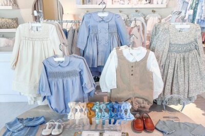 Display of children’s clothing in pastel colors, including dresses, shirts, a vest set, shoes, and hair accessories at Children's Edit.