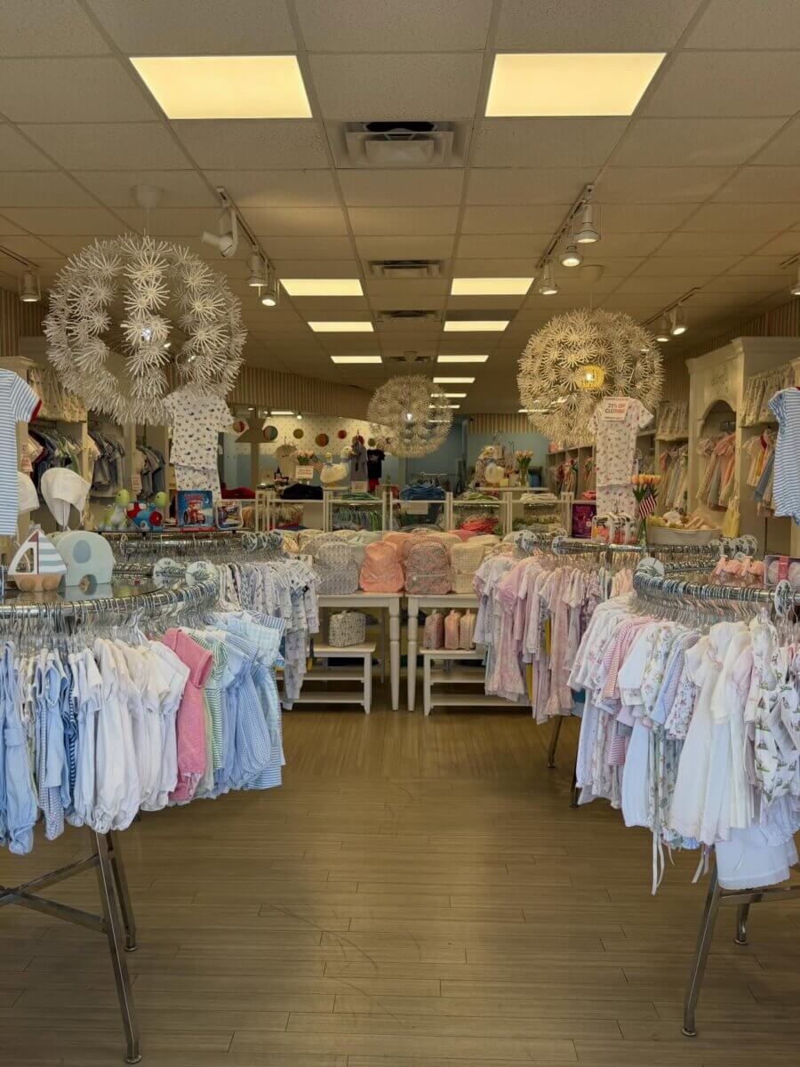 8 Birmingham Children's Boutiques for Every Age - 4 Interior of The Lili Pad with pastel-colored garments, decorative white chandeliers, and neatly arranged displays.