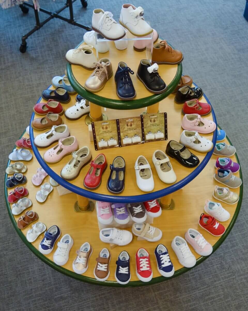 8 Birmingham Children's Boutiques for Every Age - 5 A circular, three-tiered display table holds various styles and colors of children's shoes, arranged neatly in rows on each level at Sikes Shoes.