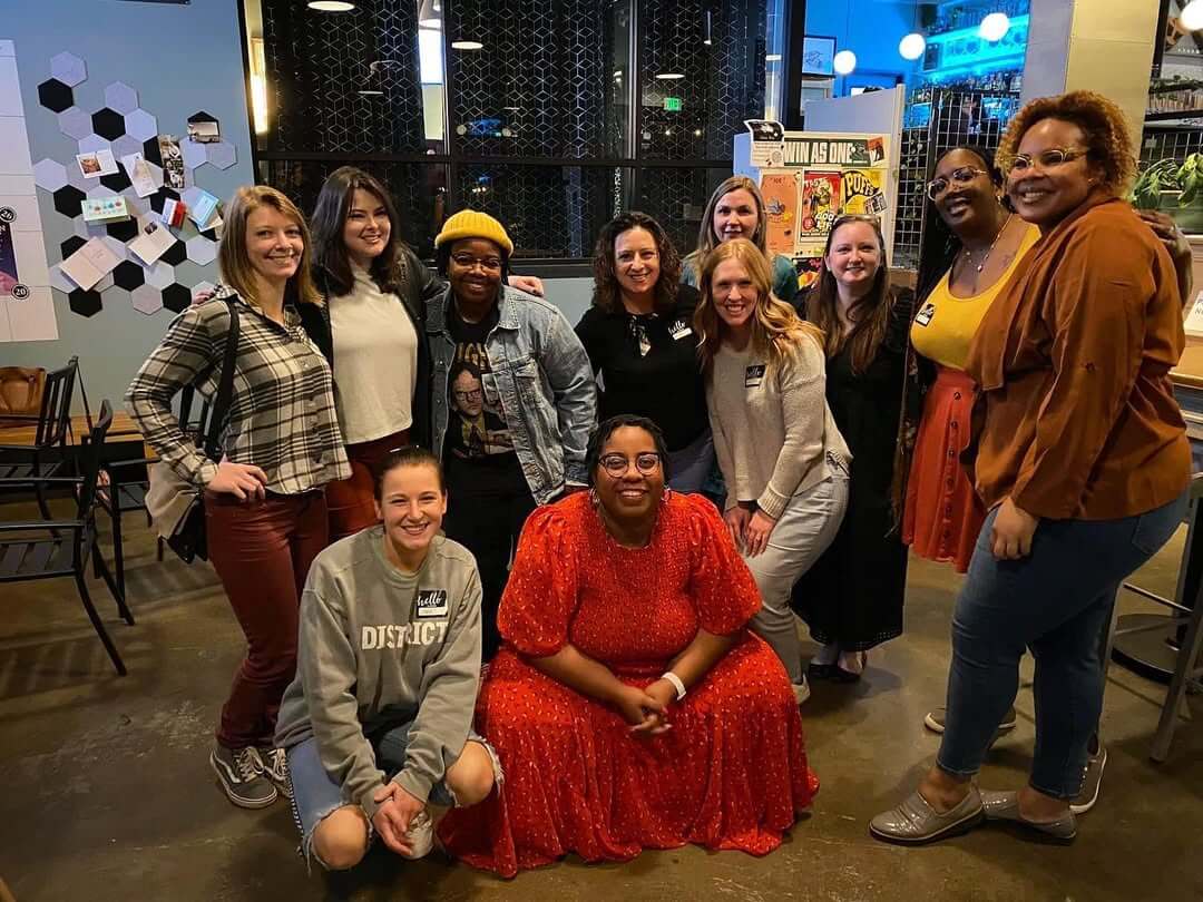 She Connects BHAM Businesses, Brews & Babes - 5 A group of twelve people pose and smile indoors. Kayla Stinnett is among the cheerful group.
