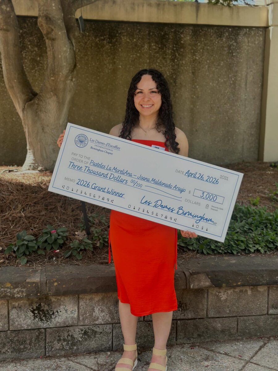 Meet the Internet Star Behind BHAM’s FIRST Mexican Mobile Bakery! - 6 Marlen Araujo stands outside, holding a large check for $3,000 as the 2026 Grand Winner from Les Dames d'Escoffier Birmingham, celebrating La MoreliAna Food Truck.