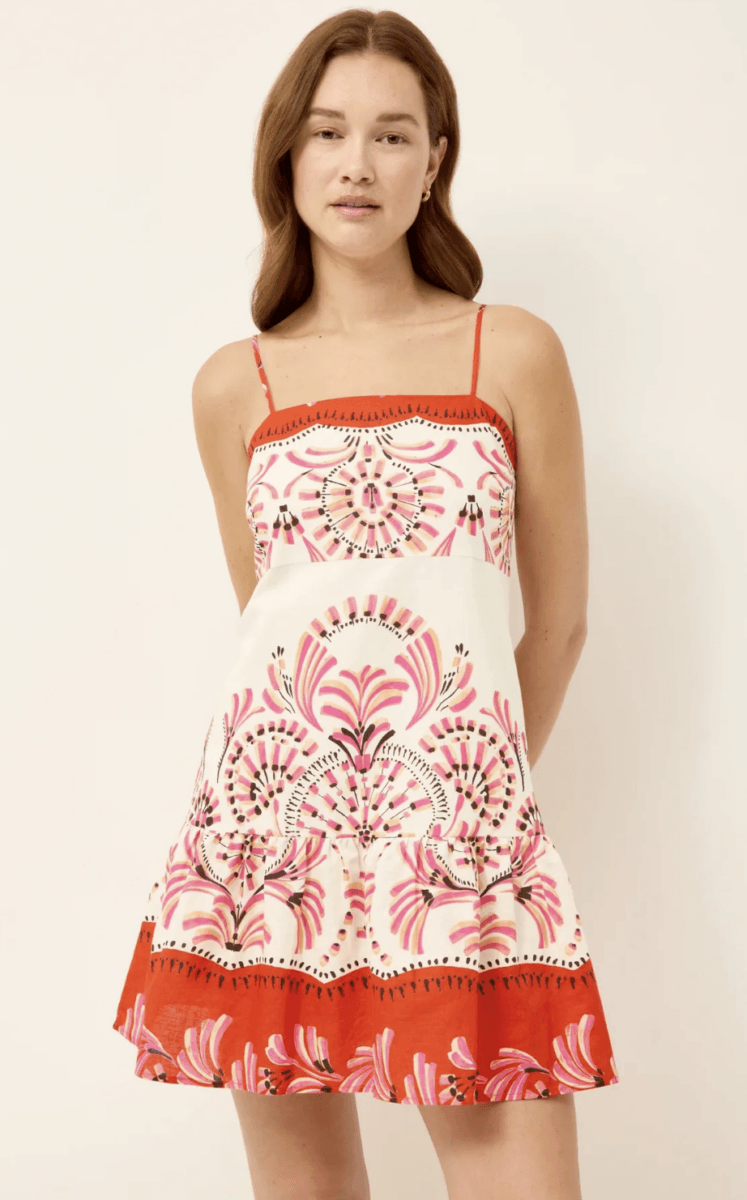 22 Birmingham FINDS for June: Breezy Dresses, Entertaining & Gifts for Dad - 5 A woman wearing a white sleeveless dress with pink and red floral patterns and thin red straps stands against a plain background.