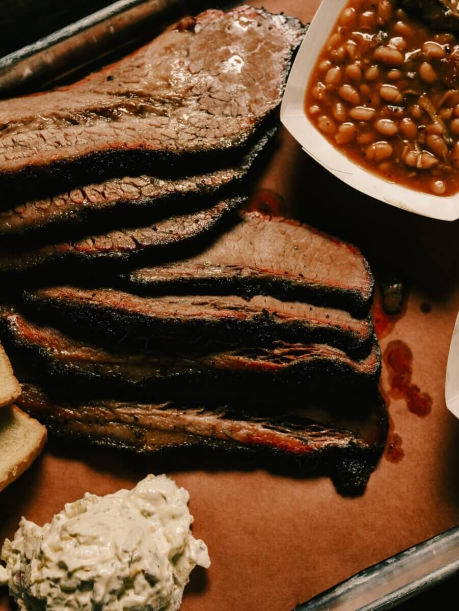13 New Birmingham Restaurants to Try This Month - 2 Slices of smoked brisket on brown paper with baked beans in a tray, potato salad, and a piece of bread.