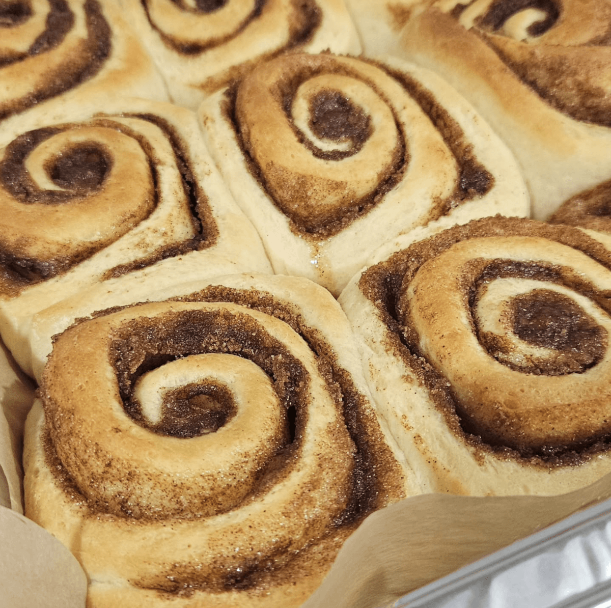 13 New Birmingham Restaurants to Try This Month - 11 A close-up of freshly baked cinnamon rolls with golden-brown swirls, still in the baking tray and lined with parchment paper—perfect inspiration for Birmingham restaurants or new restaurant concepts.