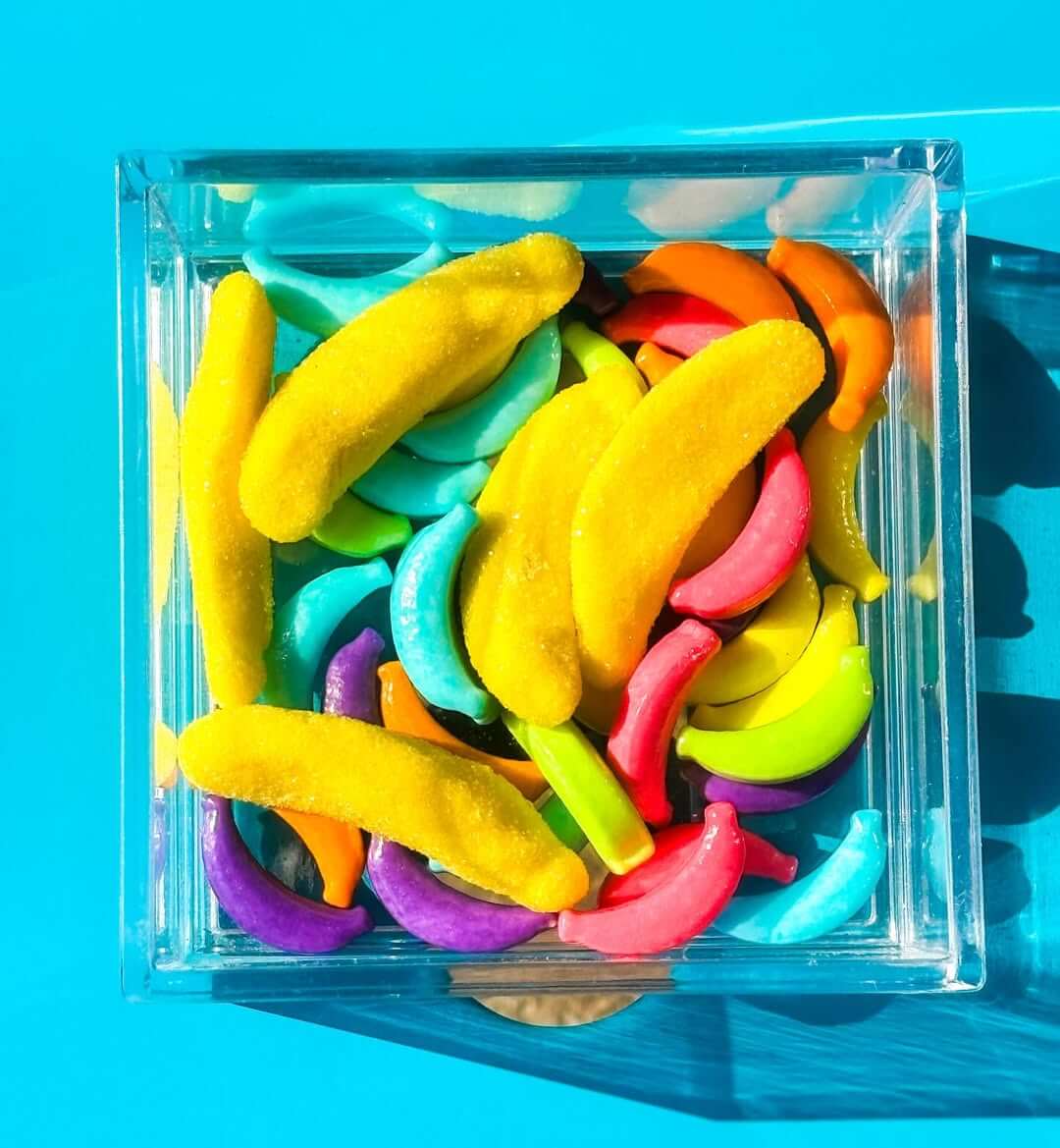 13 New Birmingham Restaurants to Try This Month - 13 A clear box filled with colorful candy shaped like bananas and crescents sits on a bright blue surface.