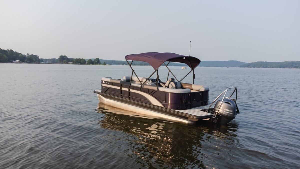 8 Ways to Get on the Water around BHAM, All Within an Hour’s Drive - 5 A pontoon boat with a canopy floats on a calm lake near the shoreline on Logan Martin Lake.