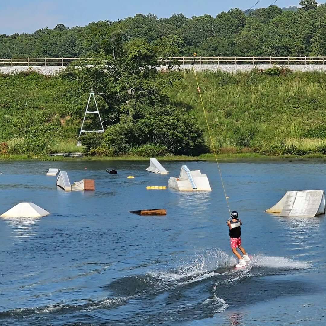 8 Ways to Get on the Water around BHAM, All Within an Hour’s Drive - 11 A person in a life vest and helmet is wakeboarding cable course at Oak Mountain State Park.