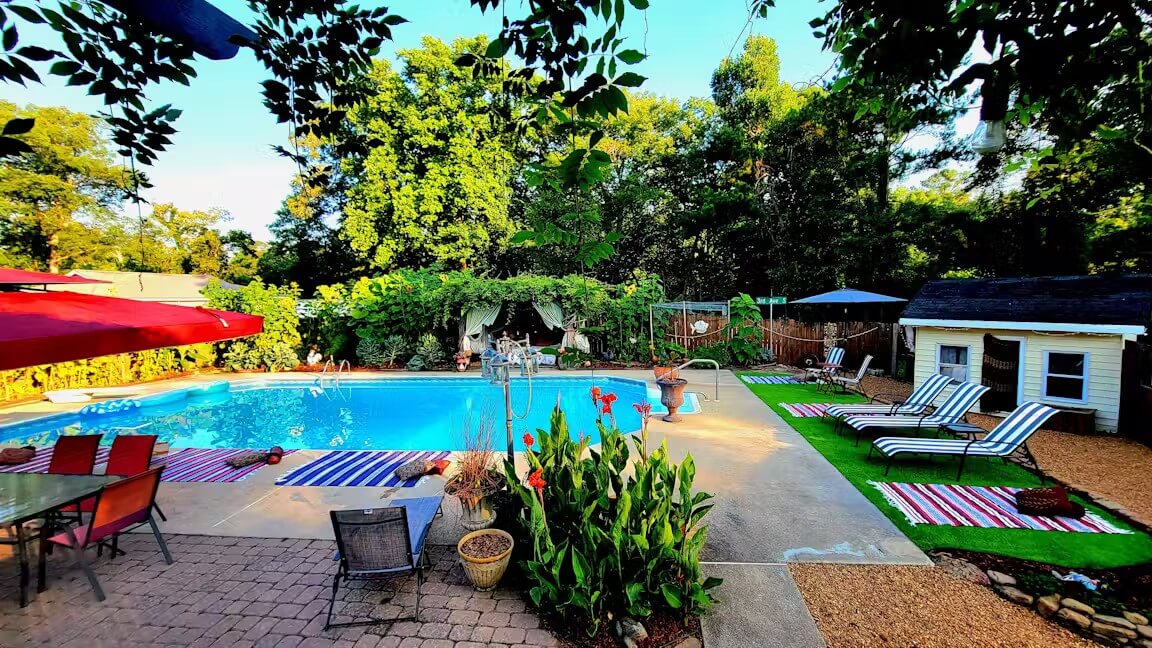 8 Ways to Get on the Water around BHAM, All Within an Hour’s Drive - 8 A backyard just an hour’s drive from BHAM, featuring a sparkling swimming pool, lounge chairs with striped towels, and a patio table with umbrella, available to rent with Swimply.