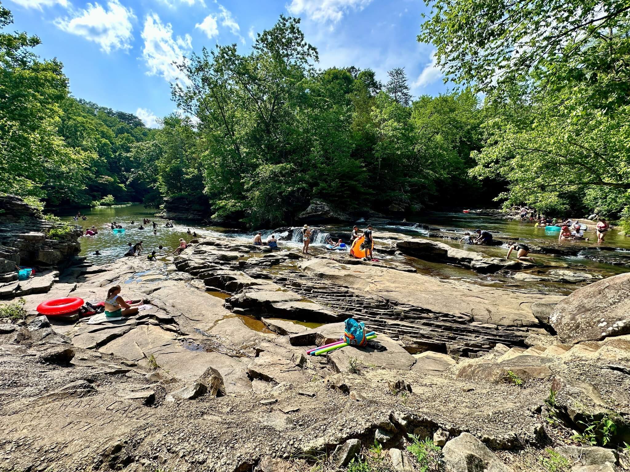 People relax, swim, and enjoy water activities on rocky riverbanks of Turkey Creek.