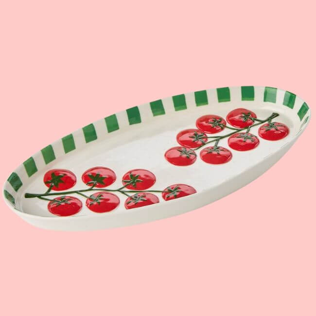 16 Louisville FINDS for June: Summer Style, Tabletop Charm & Little Luxuries - 11 Oval ceramic platter with a green striped rim and painted red tomatoes, featured in Louisville Finds April, set against a solid pink background.
