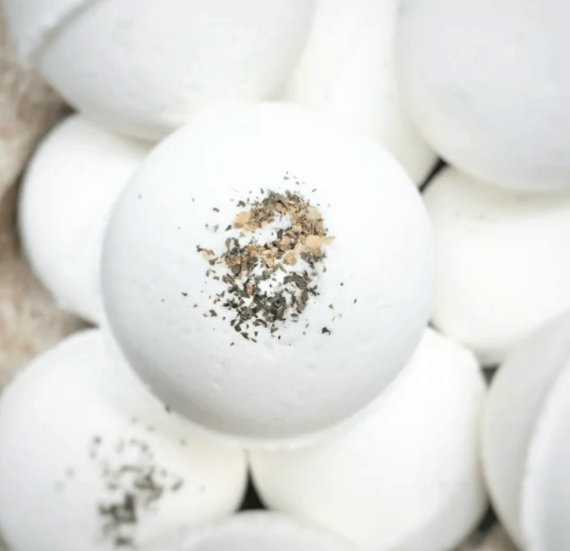 16 Louisville FINDS for June: Summer Style, Tabletop Charm & Little Luxuries - 17 A close-up of several white bath bombs, with one in the center topped with dried herbs and small brown bits—perfect everyday luxuries for your summer picks or a relaxing night in Louisville.