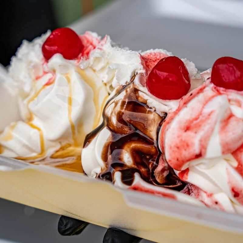 10 Louisville Ice Cream Spots to Beat the Heat - 4 Three scoops of vanilla ice cream topped with whipped cream, cherries, chocolate syrup, strawberry sauce, and caramel sauce—perfect for a sweet summer treat at one of your favorite Louisville ice cream spots.