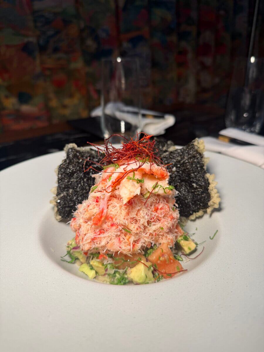 25+ Louisville Restaurants Open on July 4th - 6 A plated dish featuring a mound of shredded crab meat atop diced avocado and tomato, with two crispy black seaweed crackers and a garnish of thin red threads—perfect for July 4th celebrations at open Louisville restaurants.