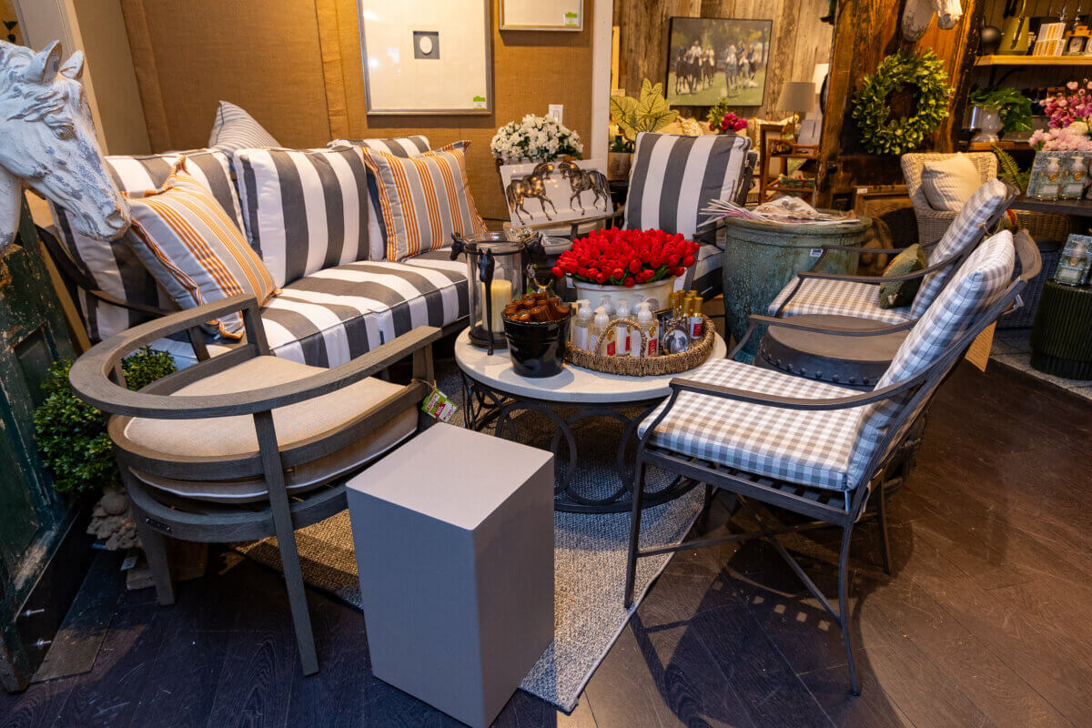 How to Refresh Your Porch in One Weekend, According to the Experts - 6 A cozy living room with striped and checkered furniture, a coffee table with a bouquet of red roses, and various decorative items arranged around the spaceβperfect inspiration for your next Weekend Porch Makeover.