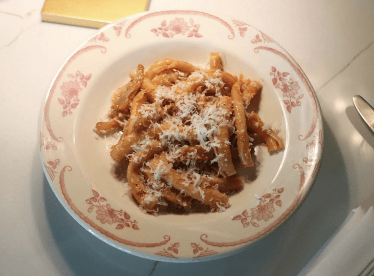 A china plate filled with pasta, and sprinkled with parmesan. 