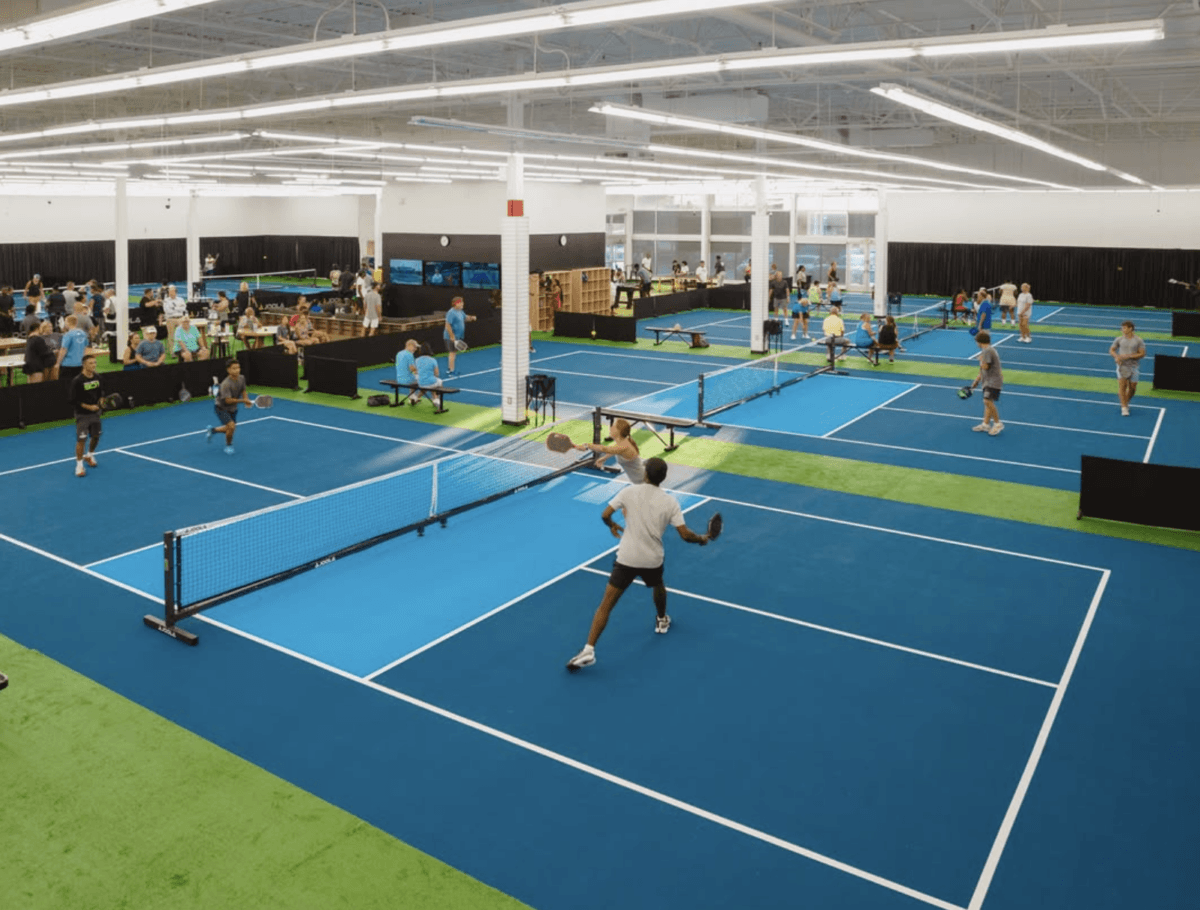 11 Places to Play Pickleball in Memphis - 4 Indoor pickleball facility with multiple courts in use; several groups of people are actively playing matches under bright lighting.