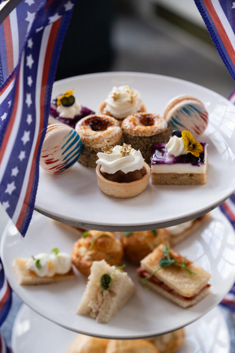 Nashville Steals, Deals & Announcements: July 2026 - 9 A tiered tray with assorted pastries, tarts, macarons, and sandwiches, framed by American flag-themed ribbons.