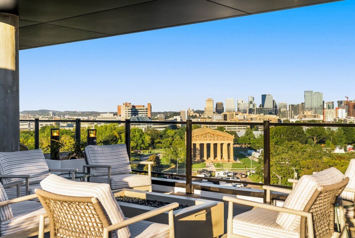 Outdoor patio with cushioned chairs and a table at 321 31st Ave N, Nashville TN, overlooks the Nashville skyline and the Parthenon in Centennial Park on a clear day.
