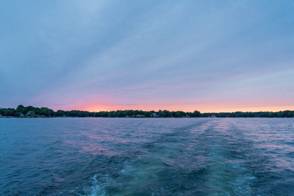 Great Southern Outdoors: Destinations for Active Travelers - 4 Open water with gentle waves and a distant shoreline at sunset, where pink and blue hues paint the skyβan inviting scene perfect for outdoor adventure vacations, with colorful reflections shimmering across the tranquil surface.