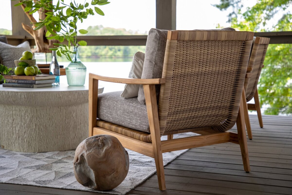 How to Refresh Your Porch in One Weekend, According to the Experts - 8 Two wicker armchairs with beige cushions sit on a deck beside a round table with a vase, books, and green applesβperfect inspiration for porch decor ideas while enjoying the scenic outdoor view.