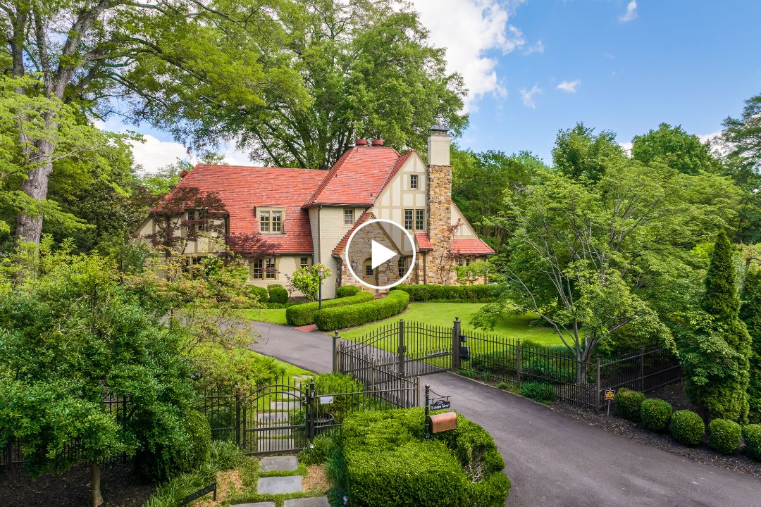 A large stone house with a red-tiled roof sits behind a black metal gate on St Andrews Fwy in Memphis, TN, surrounded by trees and manicured hedges along the paved driveway.