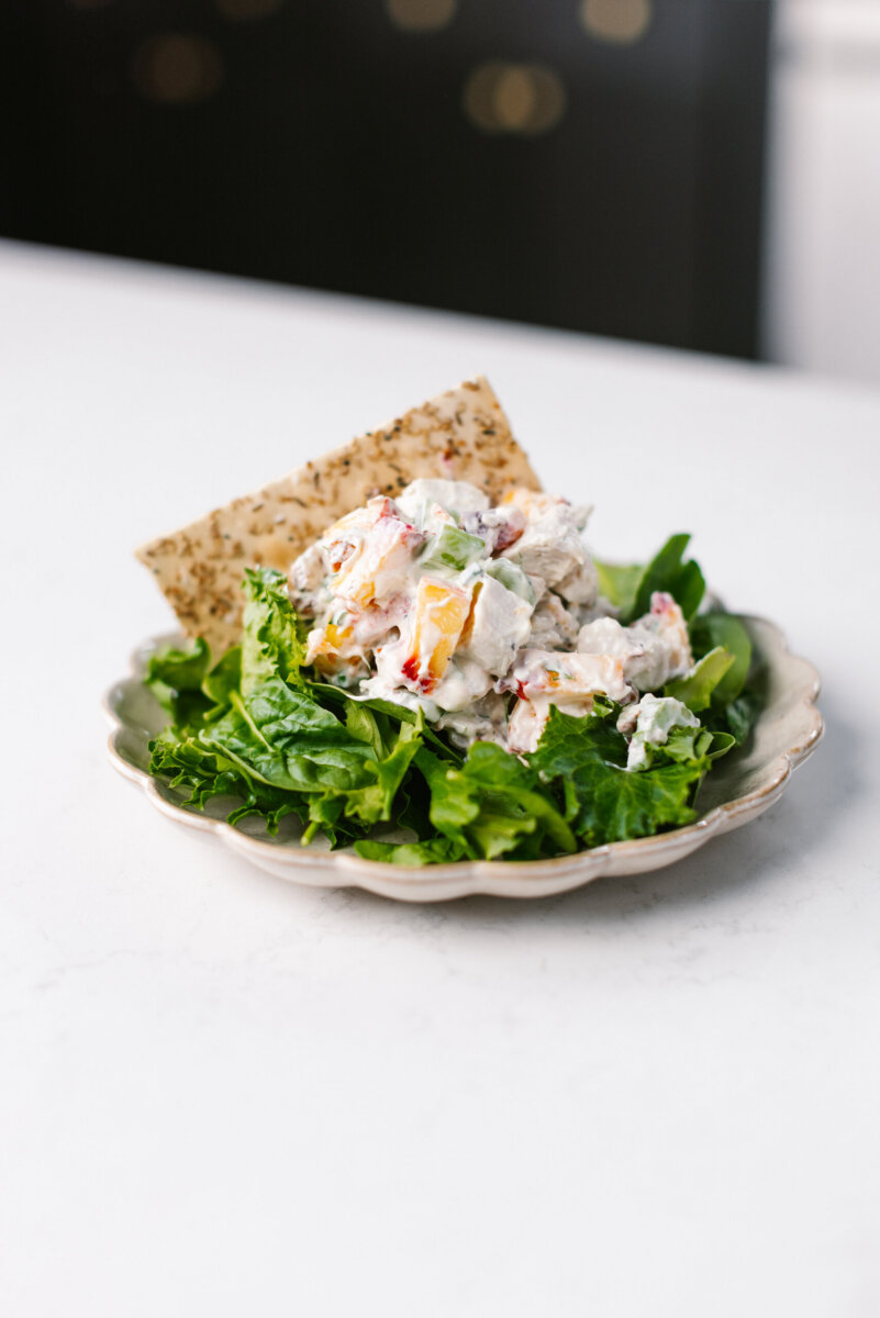 RECIPE: Peach Chicken Salad from The Peach Truck - 2 A plate with leafy greens topped with a creamy peach chicken salad and a piece of flatbread on the side.