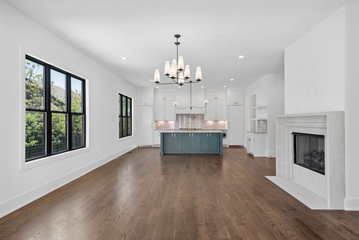 510 Stonewall Way, Brentwood TN - 2 Modern open kitchen and dining area with hardwood floors, white walls, black-framed windows, a central island, chandelier, and a white fireplace—welcome to refined living at 510 Stonewall Way in Brentwood TN.