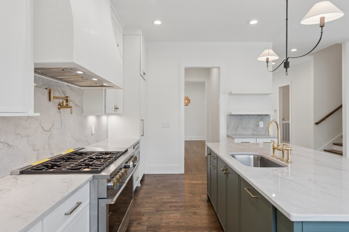 510 Stonewall Way, Brentwood TN - 3 Modern kitchen at 510 Stonewall Way in Brentwood, TN, featuring white cabinets, marble countertops, stainless steel gas stove, gold fixtures, island sink, pendant lights, and hardwood floors.