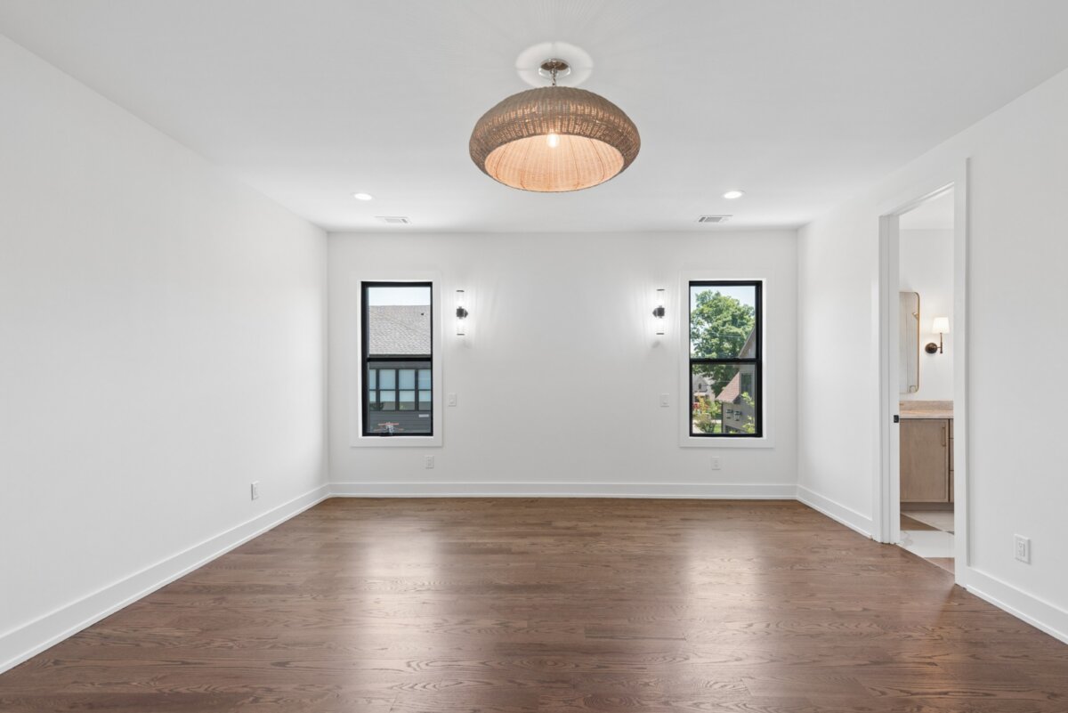 510 Stonewall Way, Brentwood TN - 4 Bright and inviting, this empty room at 510 Stonewall Way in Brentwood, TN features white walls, a sleek hardwood floor, two large windows for ample natural light, a modern ceiling light fixture, and an open doorway leading to the bathroom.