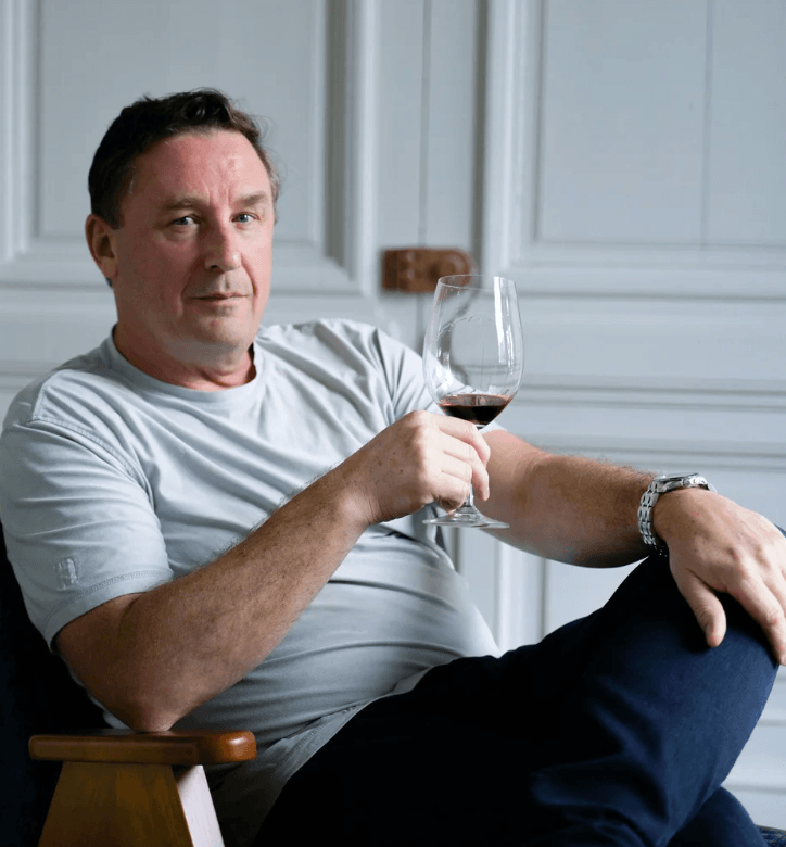 Your New Favorite Wine Destination Just Opened in Pepper Place - 3 A man in a light gray shirt sits in a chair, holding a glass of Balance Wine with a neutral expression in a room with white paneled walls.