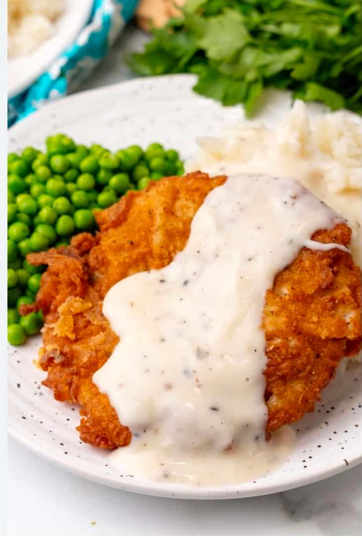 11 New Birmingham Restaurants to Try This Month - 9 A plate with breaded chicken topped with white gravy, served with mashed potatoes and green peas—a comforting classic.
