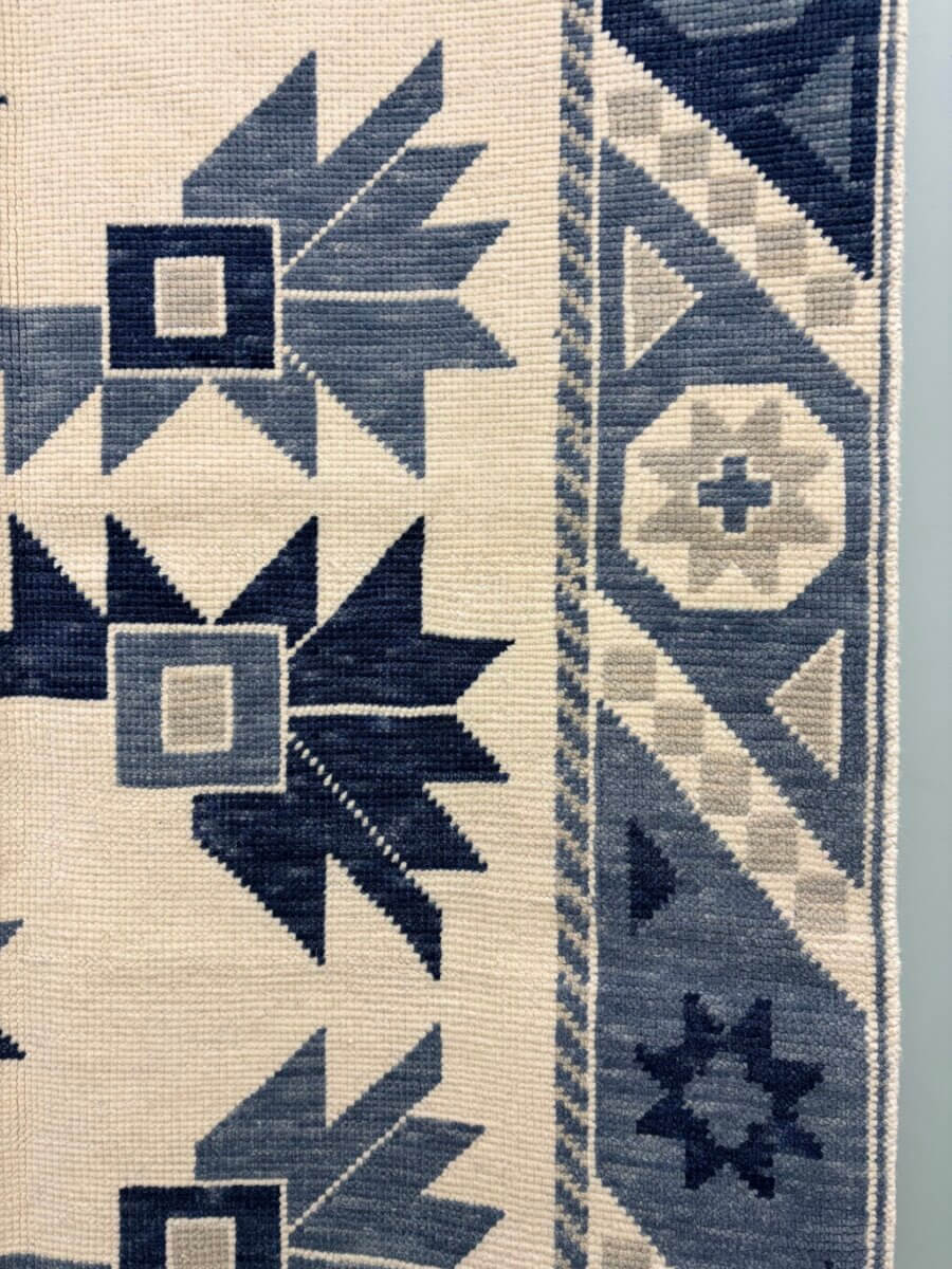 This Award-Winning BHAM Rug Company Launched a New Collection Celebrating America’s 250th Year - 3 A close-up of a woven fabric from the new collection by Birmingham Rug Company, featuring geometric patterns in blue and cream with a decorative border on the right side.