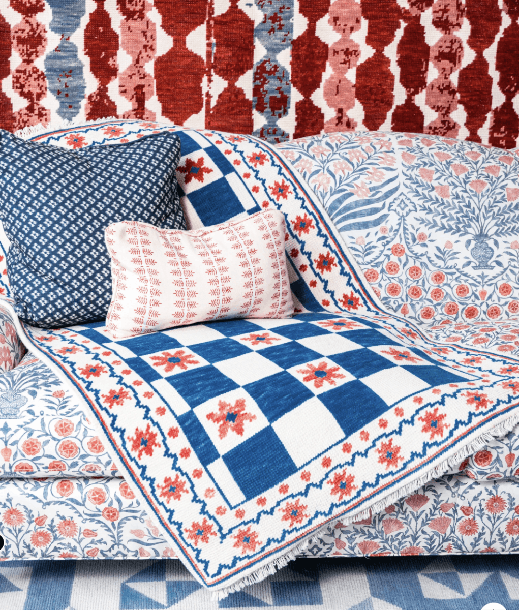 This Award-Winning BHAM Rug Company Launched a New Collection Celebrating America’s 250th Year - 4 A patterned sofa with a blue and white quilt, two decorative pillows, and a red and white abstract wall hanging in the background from the Birmingham Rug Company’s new collection, perfect for celebrating America’s 250th year.