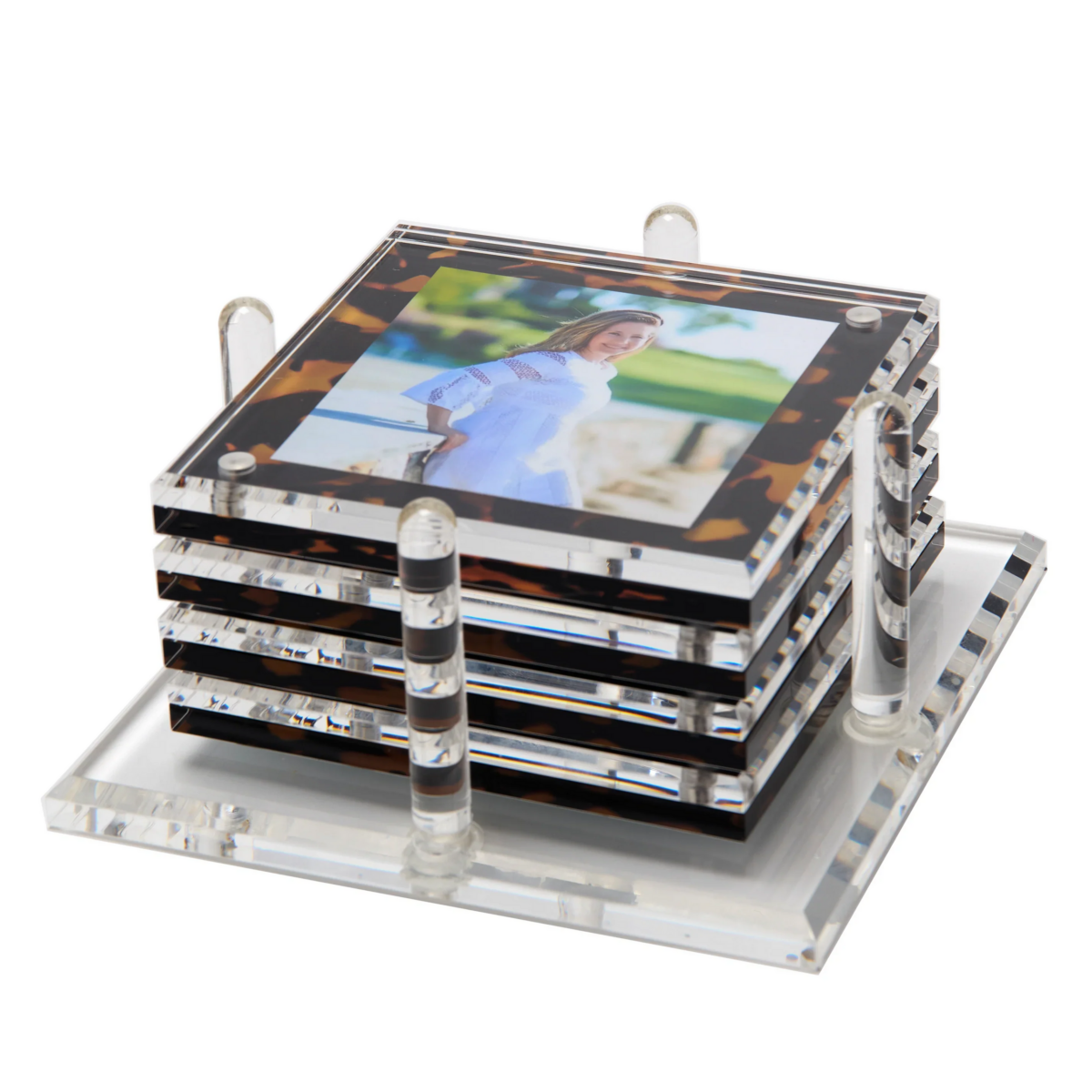 Set of acrylic coasters with a photo on top, stacked on a matching square holder with clear rods securing the corners. Perfect for preserving special memories in style.