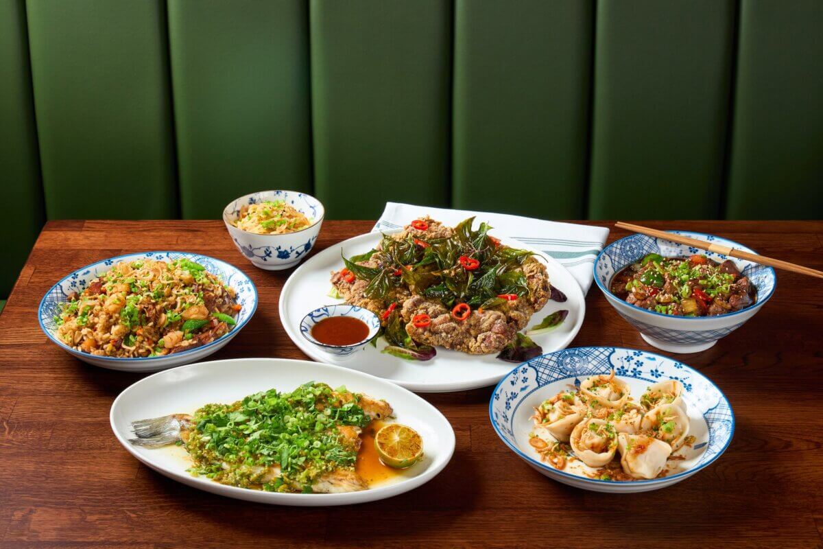 A selection of Chinese dishes, including fish, fried rice, noodles, dumplings, and a plate of fried meat with vegetables, served on a wooden table—perfect for those seeking fresh flavors in Louisville dining or exploring new restaurants in the area.