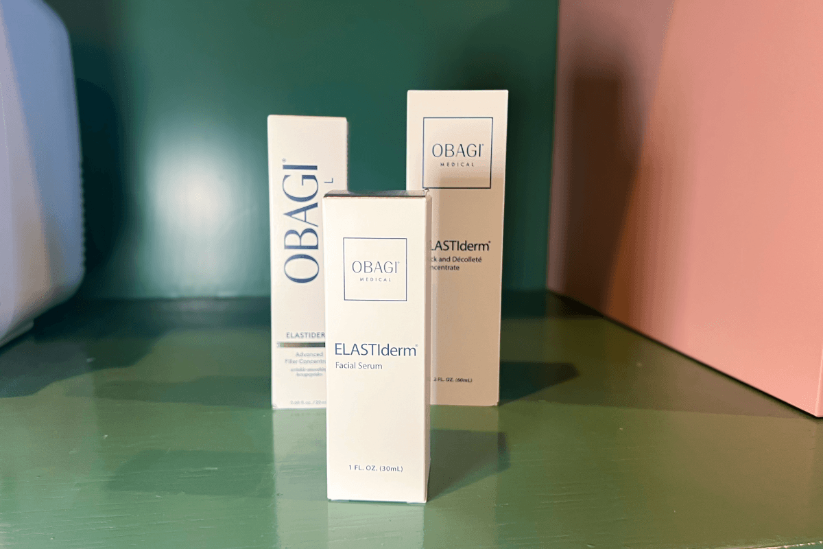20 Memphis FINDS to See You Through the End of Summer - 18 Three Obagi Medical ELASTIderm skincare product boxes are displayed on a green surface with a pink background panel.
