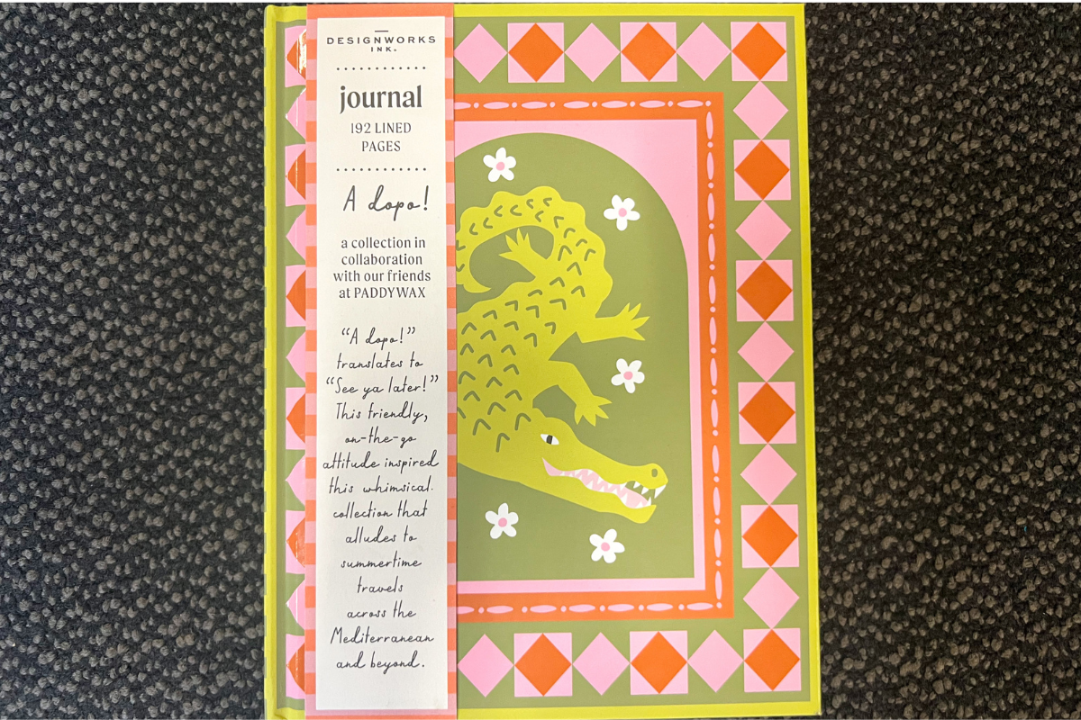 20 Memphis FINDS to See You Through the End of Summer - 19 A journal with a green crocodile illustration on a pink and orange patterned cover, labelled “192 lined pages,” displayed on a dark textured surface.