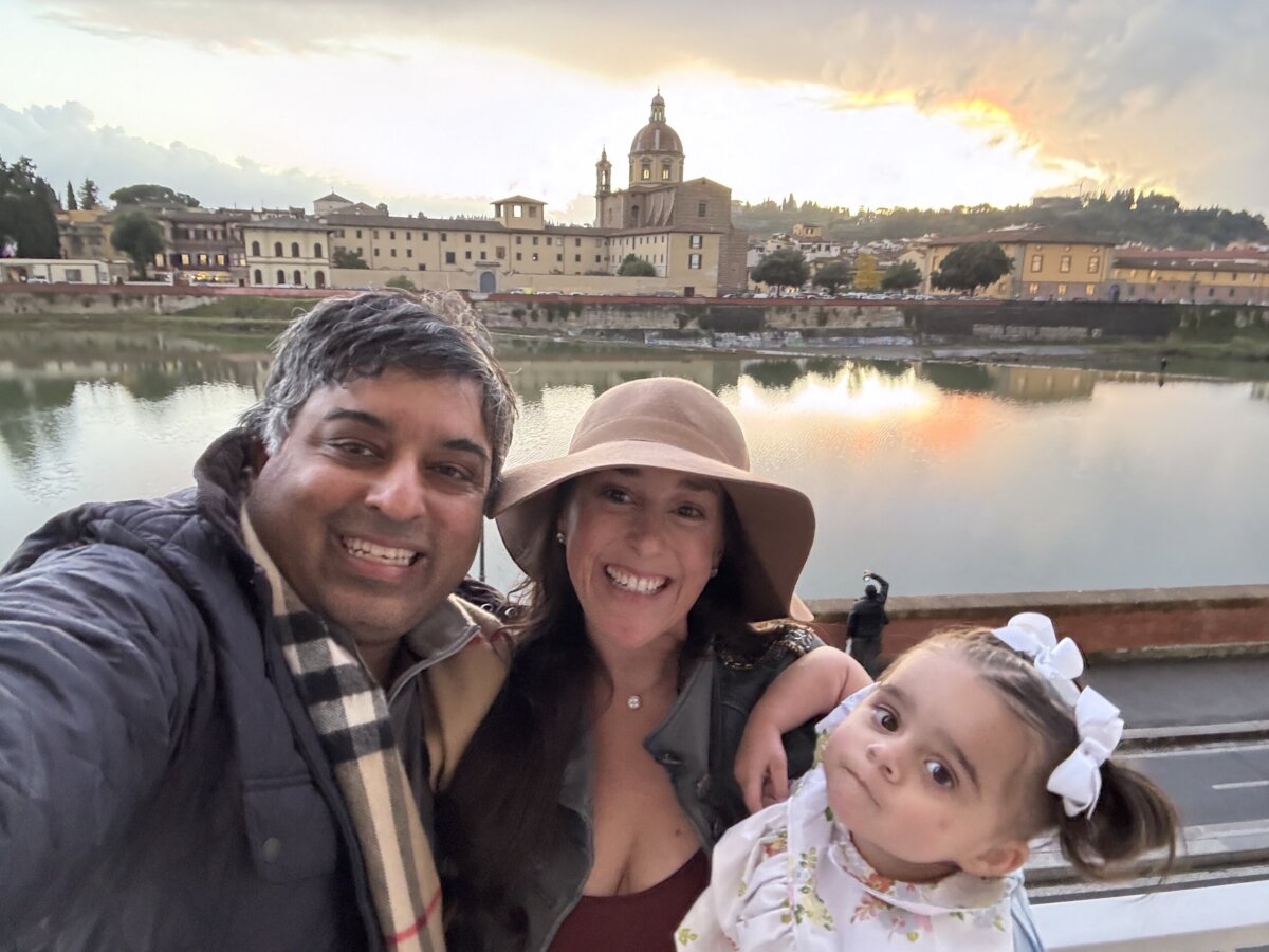 She's Building Memphis's Newest Stomping Grounds - 5 A family of three poses for a selfie by a river at sunset, their FACES lit with joy, as historic buildings and a domed church form the picturesque backdrop.