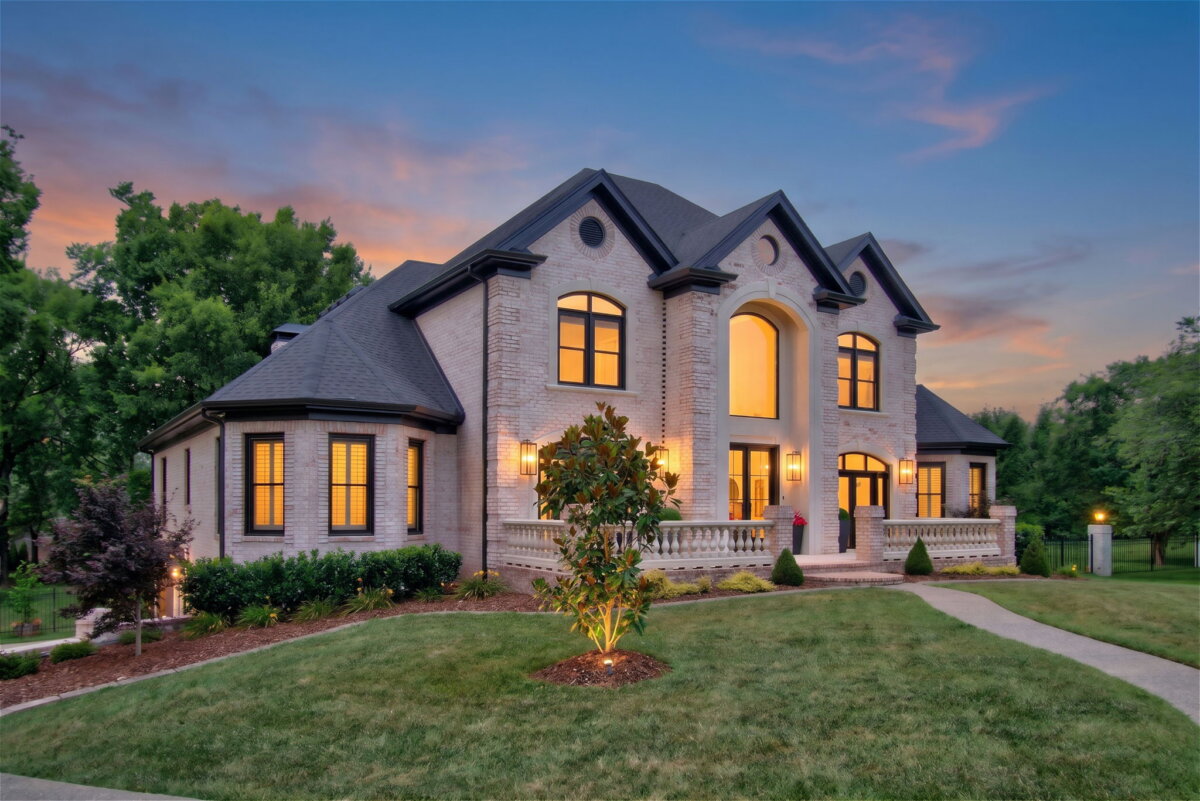 Just Listed! This Renovated Brentwood Home Has a Private Primary Wing, 4 Fireplaces & a Park-Like Backyard - 2 Renovated large two-story brick Brentwood home featuring multiple arched windows, a central entrance, outdoor lighting, and a well-manicured lawn at sunsetβall overlooking a park-like backyard.