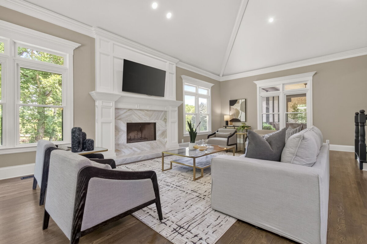 Just Listed! This Renovated Brentwood Home Has a Private Primary Wing, 4 Fireplaces & a Park-Like Backyard - 12 Modern living room with a fireplace, wall-mounted TV, large windows, light-colored furniture, abstract rug, and wooden floors in this beautifully Renovated Brentwood Home. Enjoy seamless access to the Park-Like Backyard from the main living space.